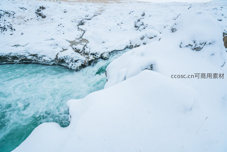白雪堆积的河岸旁激流汹涌澎湃