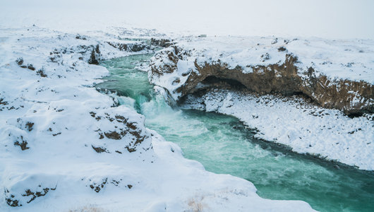 雪中拱桥下碧水穿流