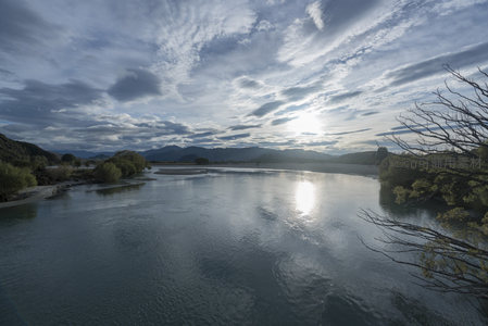 晨曦破云照河川，枯枝剪影添诗意