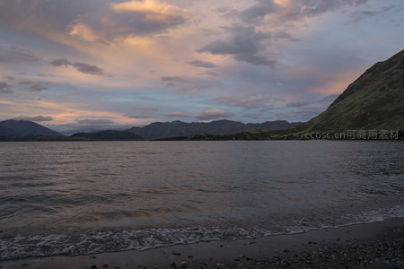 夕阳染湖，浪花轻吻石滩岸