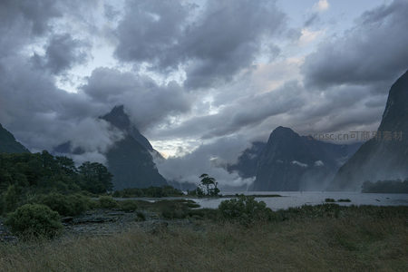 多云天气下的峡湾全景，群山环抱湖水幽深