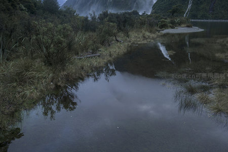 静谧湖面倒映着远方的瀑布与山林