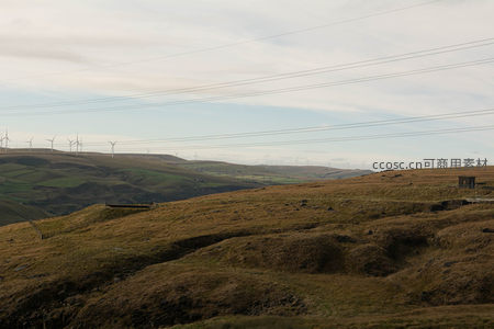 电线横跨荒野山坡连接远方风车