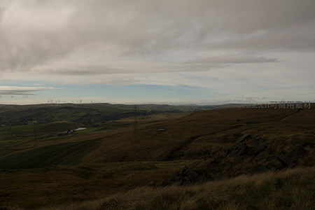 云层下的山丘与风力发电机群