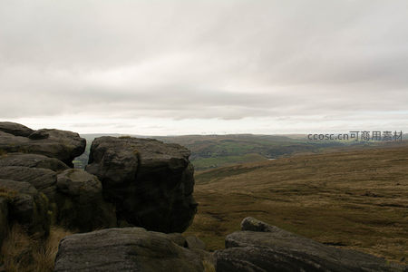 阴云密布的山巅巨石与远方风车景观