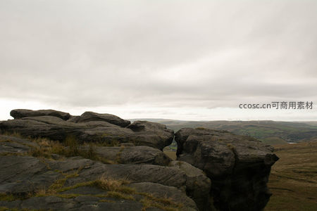 阴云密布下崎岖山岩与远方风车