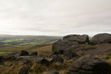 巨岩俯瞰山谷绿野与远方风车