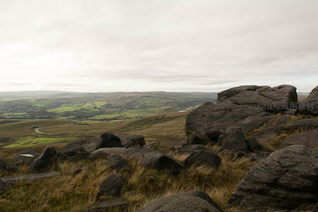 岩石丛中眺望辽阔山谷与风能设施