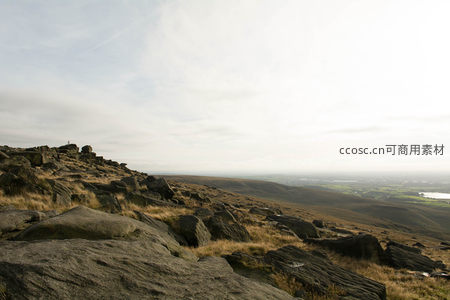 晨雾中岩石坡地与远方湖泊的静谧画卷