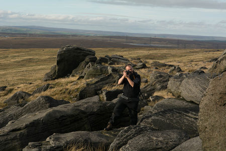 摄影师在荒野岩石上专注拍摄