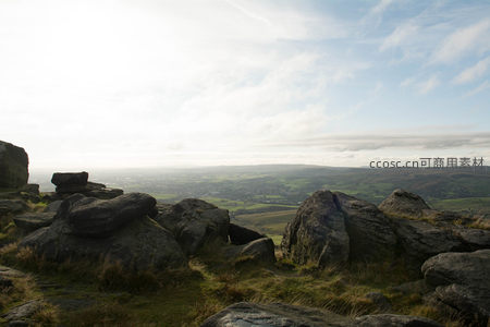 山巅巨石俯瞰绿野与远方风车
