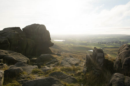 巨岩夹缝间眺望阳光洒落的平原村落