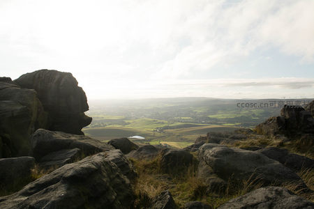 岩石缝隙间眺望绿野与风车群