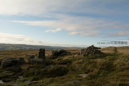 山顶草甸上的石堆与远景风车构成画卷