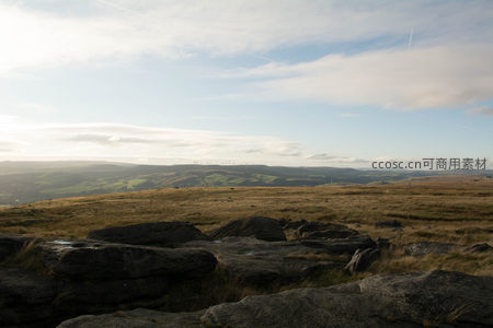 晨光中的山地岩石与远方风力发电站