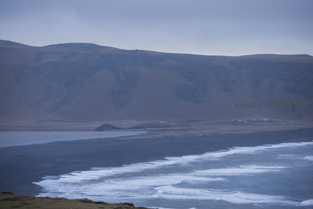 黑沙滩与远山下的宁静海湾