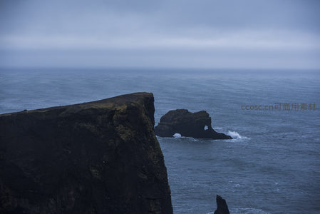 雾霭笼罩下的悬崖与远处海蚀洞