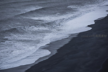 巨浪拍打黑色沙滩的瞬间