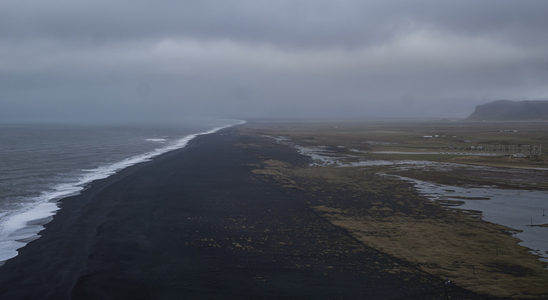 阴沉天空下的黑沙海岸线