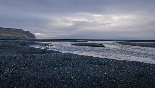 黑沙滩上的河流蜿蜒流向远方