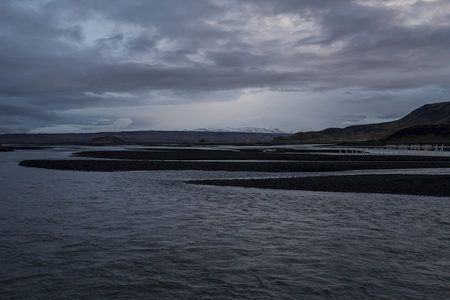 阴云密布下的黑沙滩河流景观