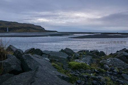 黑沙滩与远山瀑布的静谧黄昏