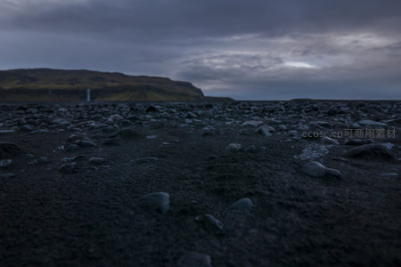 暮色中黑石滩与远山瀑布的剪影