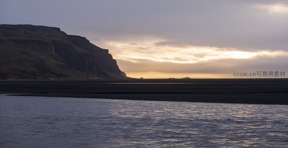 悬崖剪影映衬夕阳余晖洒满海滩