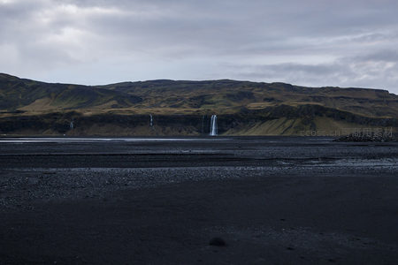 黑沙滩上的远山瀑布