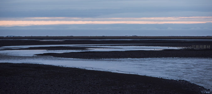 蜿蜒溪流穿黑土，暮云低垂染天边