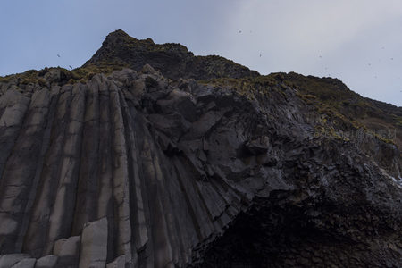 仰望火山岩壁的雄伟柱状结构