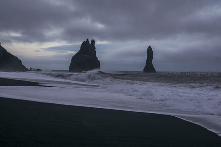 海浪轻抚黑沙与孤岩的静谧时刻