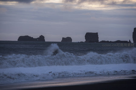 海浪怒卷黑沙岸，孤石屹立苍茫海天间
