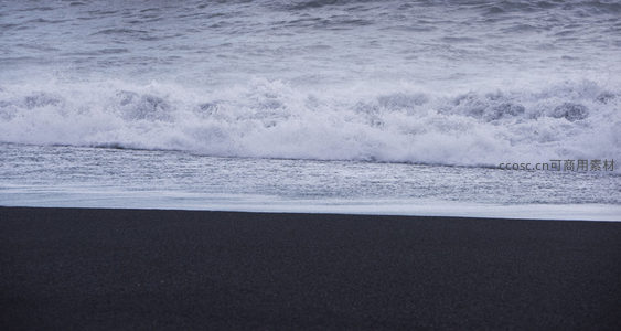 近景白浪翻滚，黑沙细腻如墨铺展海岸