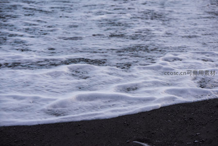 浪花泡沫在黑沙上流淌