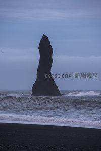 孤石矗立黑沙滩，海浪拍岸云天低