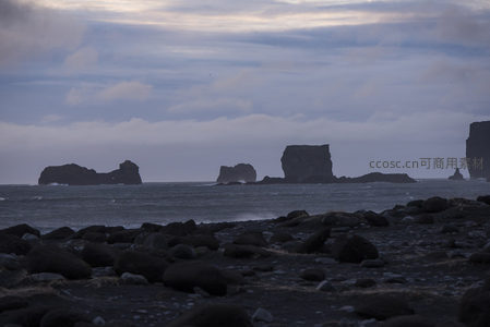 暮色中礁石剪影，海风轻拂卵石滩