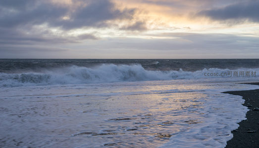 夕阳下的黑沙滩海浪拍岸
