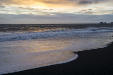 金色夕阳映照黑沙海岸线