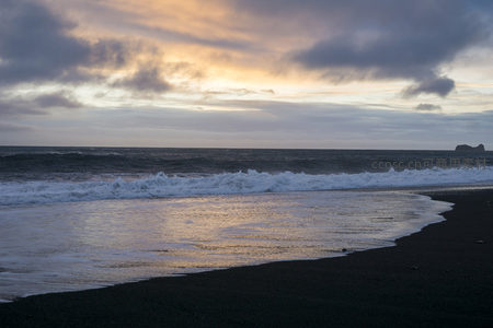 金色余晖洒满黑沙海岸线