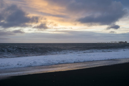黑沙滩日落，海浪轻抚海岸线