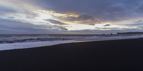 黑沙滩日落，海浪轻抚海岸线