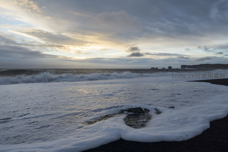 泡沫缠绕礁石，夕阳余晖映沙滩