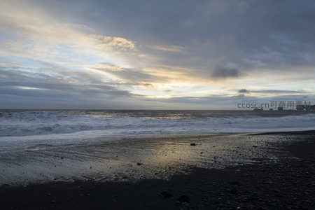 夕阳穿透云层照亮黑沙滩