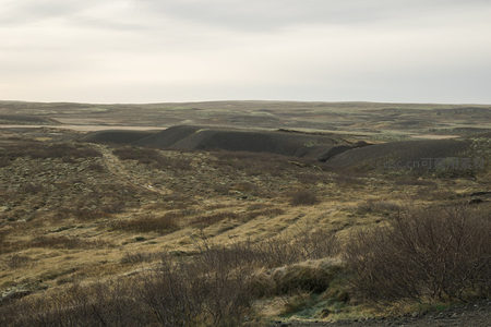 广阔荒原上黑色火山锥与枯黄草地交织