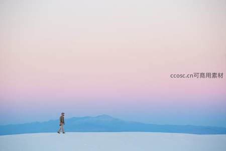 孤独行者漫步于粉紫霞光下的雪原