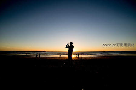 夕阳海滩剪影人物拍照留念