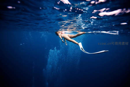 自由潜水者畅游深蓝海底，水波光影如梦似幻