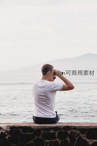 男子海边用望远镜眺望远方山景