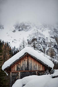 雪覆木屋静立山间，远峰云雾缭绕如画